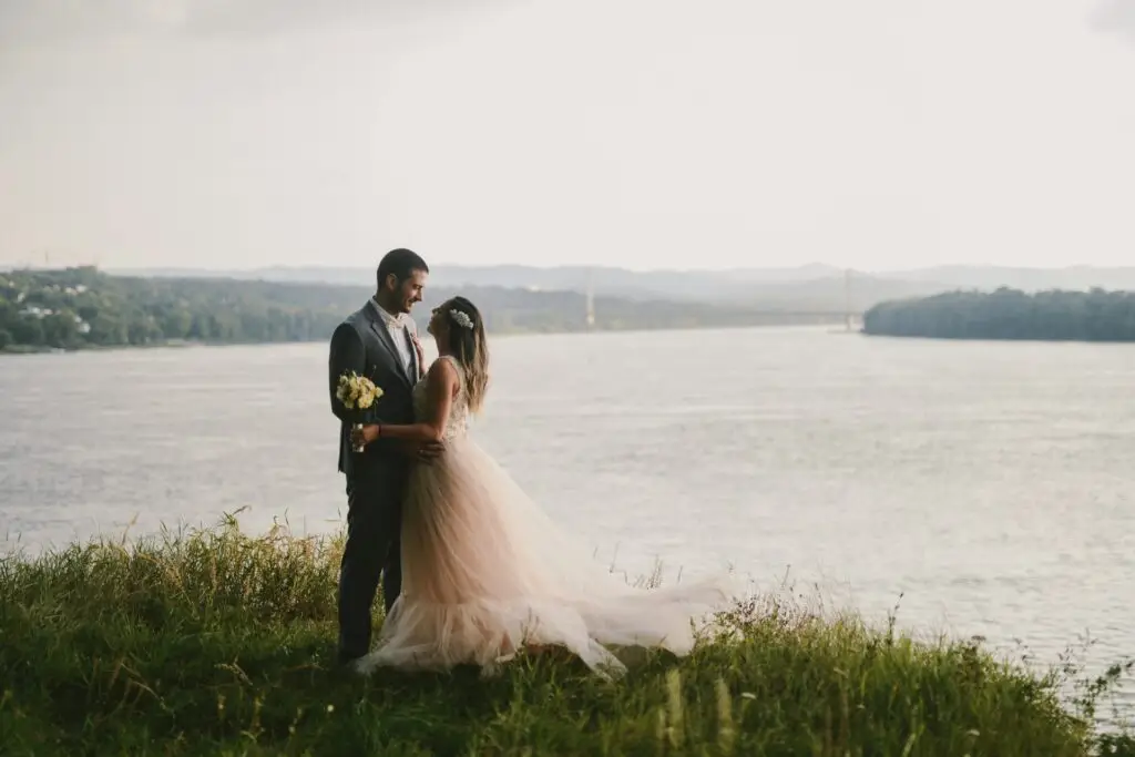 Bride and groom by the water on their wedding day – ideal setting for large wedding party transportation planning